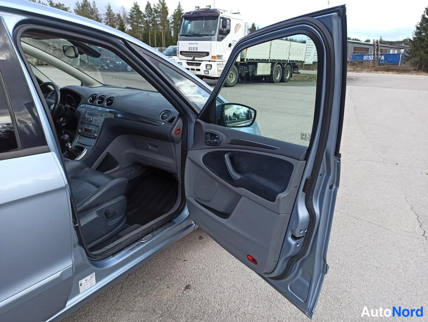 Sivulta: Ford S-MAXin etuosan sivukulma avoimella kuljettajanovella; auton kori on sinisenharmaa ja ohjaamo näkyy ovesta sisään.