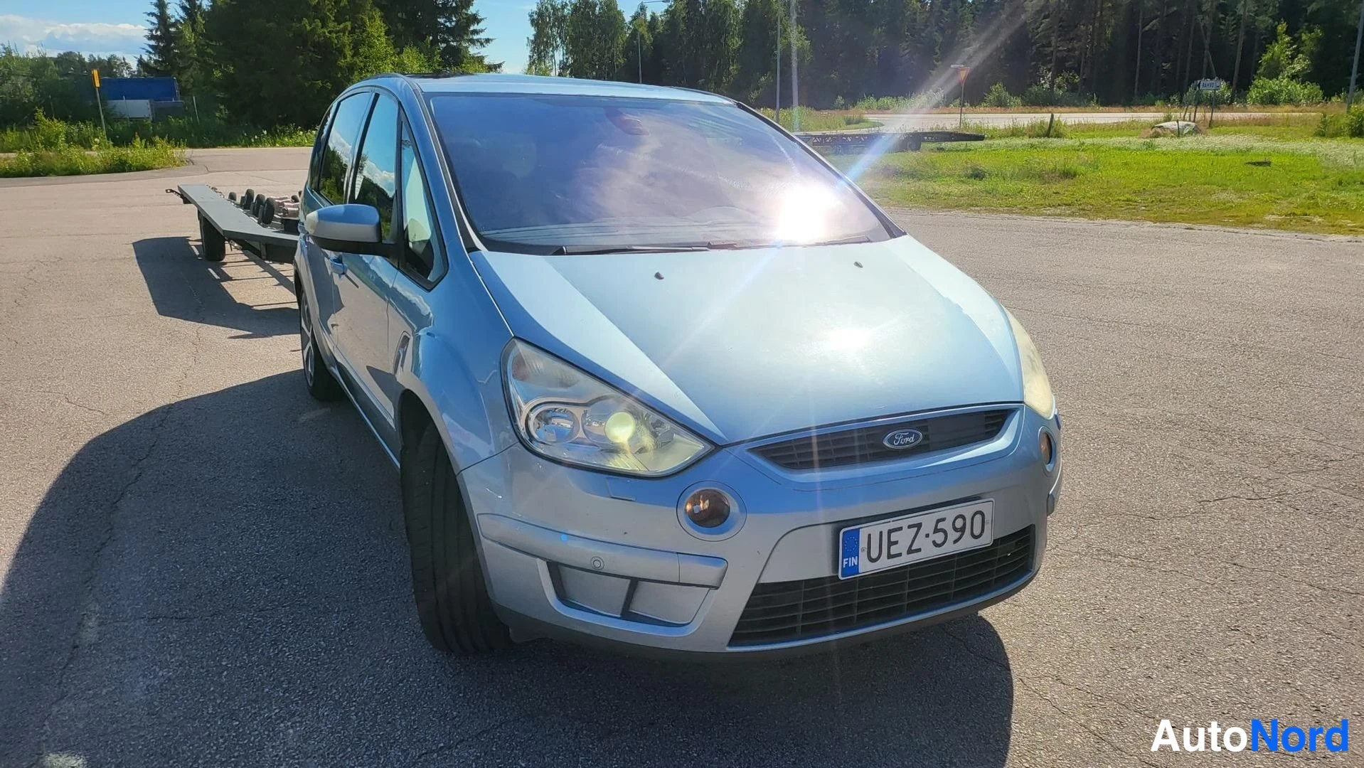 Etuviisto, nokka oikealle: Sininen Ford S-MAX kolmivartin etunäkymässä vasemmasta sivusta, rekisteritunnus, auringonheijastus tuulilasissa.