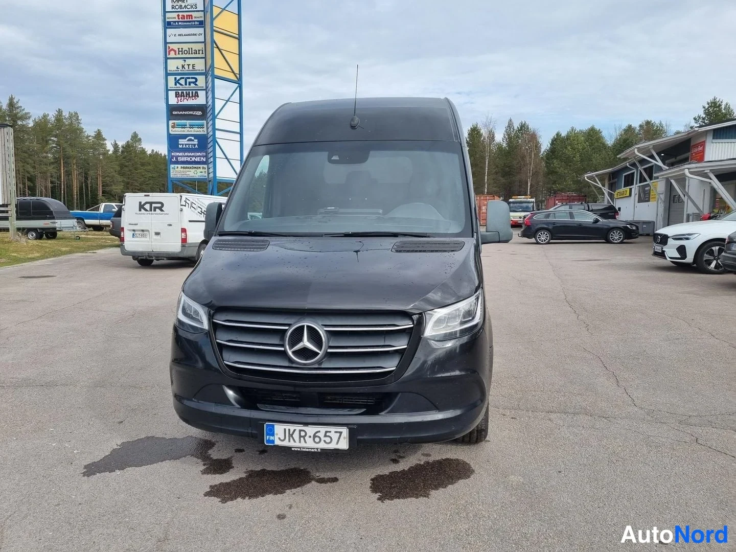 Edestä: Musta Mercedes-Benz -pakettiauto suoraan edestä, rekisterikilpi.