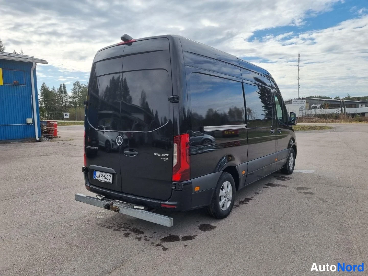 Takaviisto: Mustan Mercedes-Benz Sprinter -pakettiauton takaosa kolmivartaloasennosta; rekisterikilpi ja merkinnät 316 CDI näkyvät.