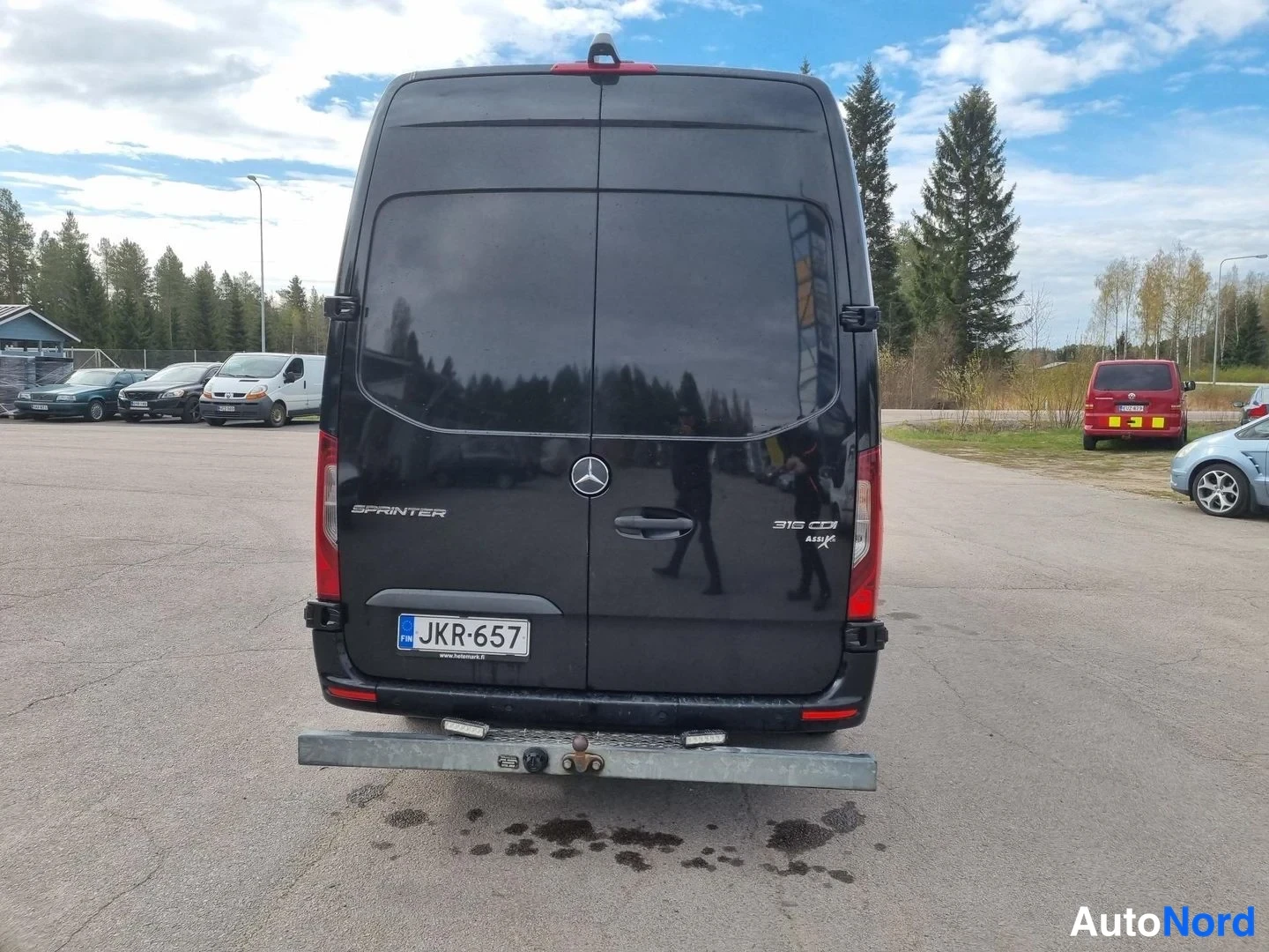 Takaa: Mercedes-Benz Sprinter -pakettiauton takaosa, rekisteritunnus, halkaisupalkki ja vetokoulu takaosassa.