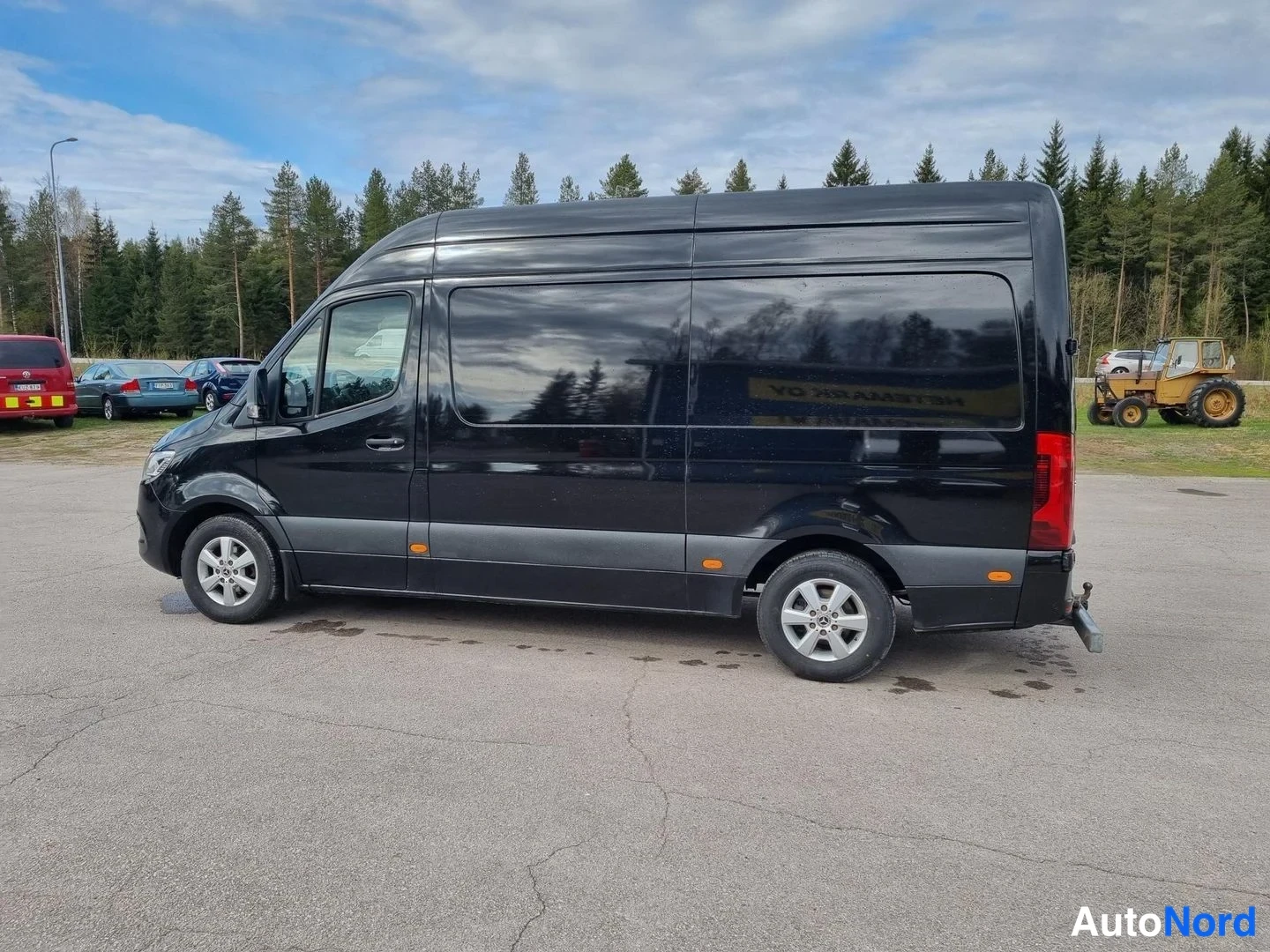 Sivulta: Mustan Mercedes-Benz Sprinter -pakettiauton kylkinäkymä, pitkä akseliväli ja korkeakatto näkyvissä.