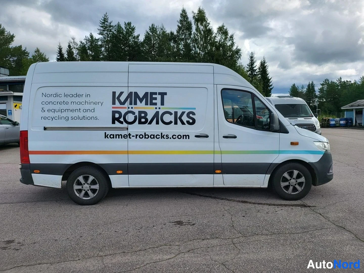 Takaviisto: Mercedes-Benz Sprinter -pakettiauto kyljestä kuvattuna, valkoinen pinta ja Kamet Röbacks -teksti ovessa.