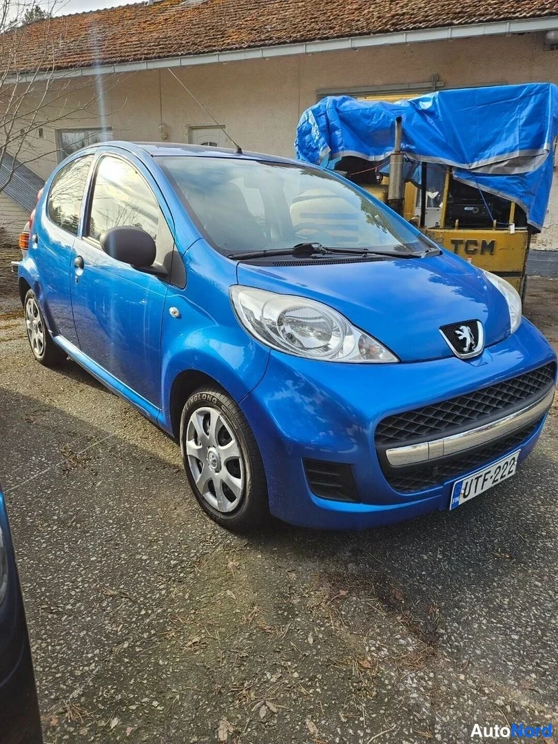 Etuviisto, nokka oikealle: Sininen Peugeot 107 etuviistöstä, keula oikealla, rekisterikilpi näkyvissä.
