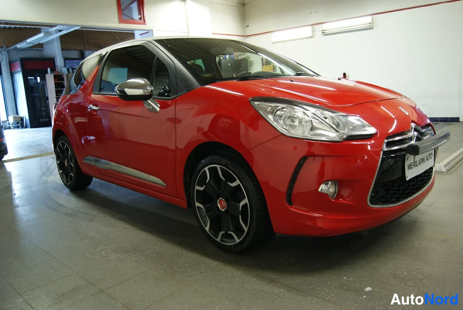 Etuviisto, nokka oikealle: Punainen Citroën DS3 etukulmasta oikealta, hopeinen rekisterikilven kehys, teksti MERILAPIN AUTO.