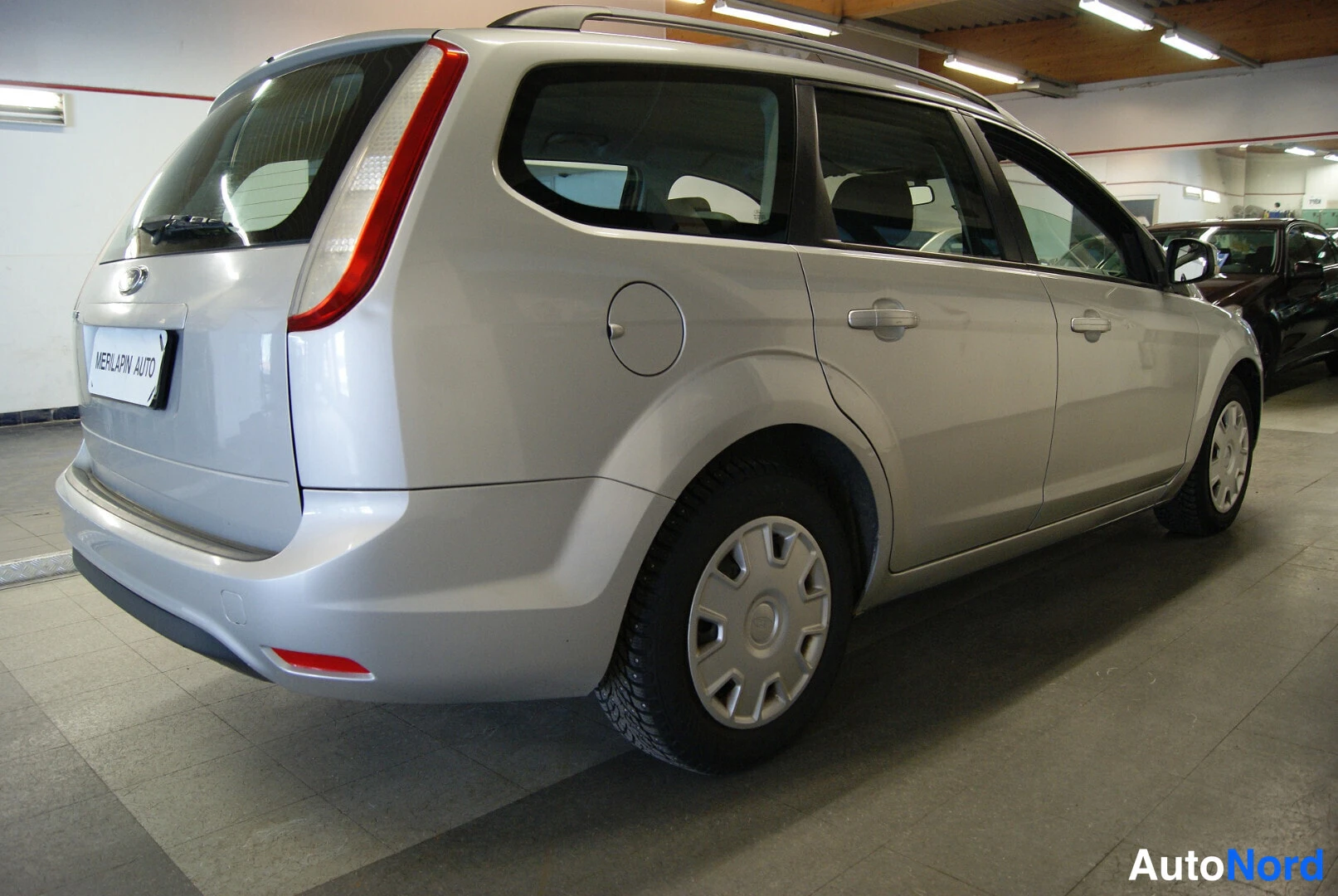 Takaviisto: Ford Focus Farmari 2008, hopeanvärinen, kulmakuva takaa oikealta; takavalot, takaluukku ja kylki näkyvissä.