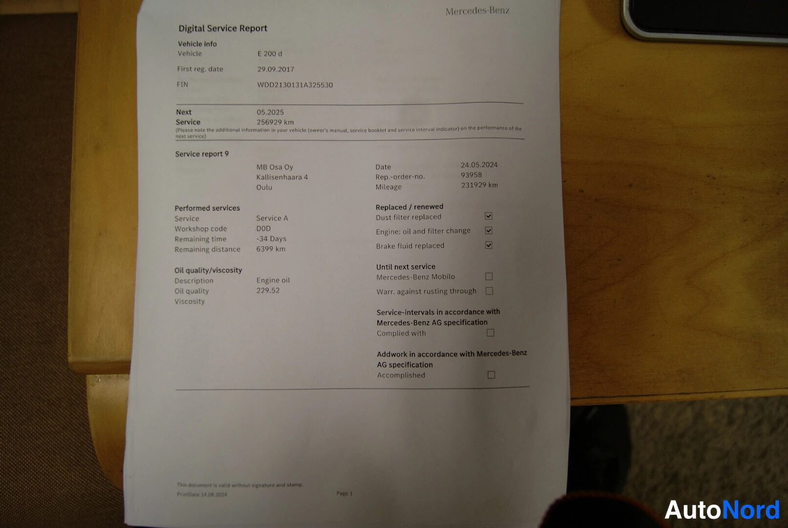 Asiakirja: Tulostettu Mercedes-Benzin Digital Service Report -huoltoraportti E 200 d -autolle puupöydällä.