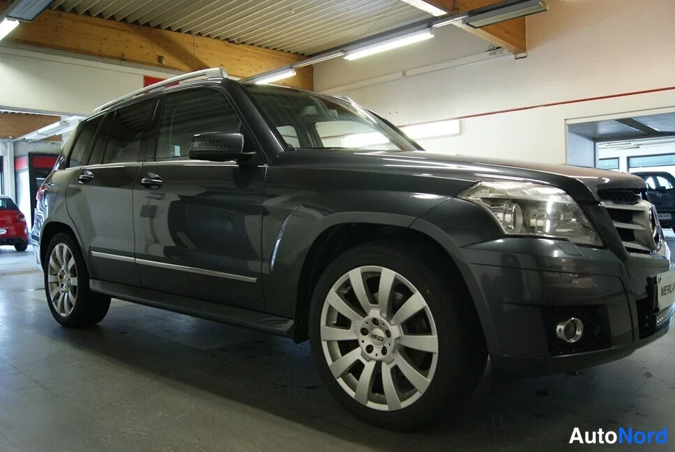 Etuviisto, nokka oikealle: Tummanharmaa Mercedes-Benz GLK etukenonäkemä, keula kuvan oikealla reunalla ja kylki näkyvissä.