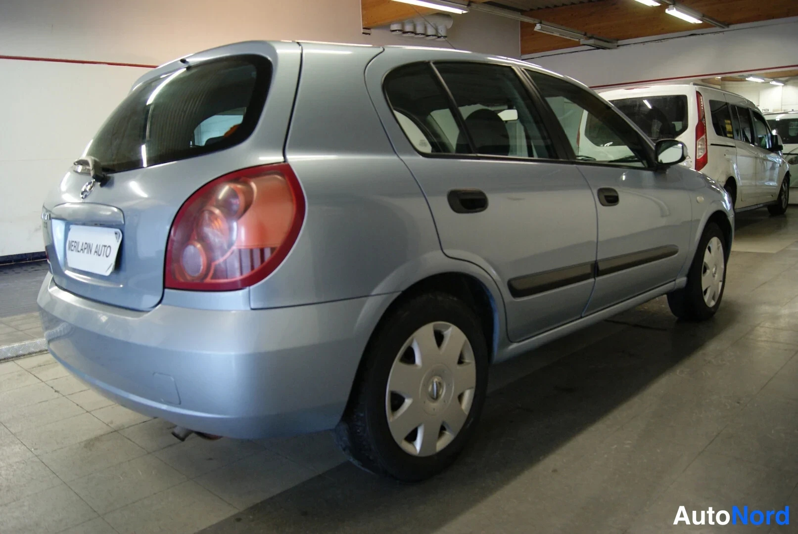 Takaviisto: Auton takakulma vasemmalta: hopeanharmaa viistoperäauto parkkihallissa, taustalla pakettiauto.