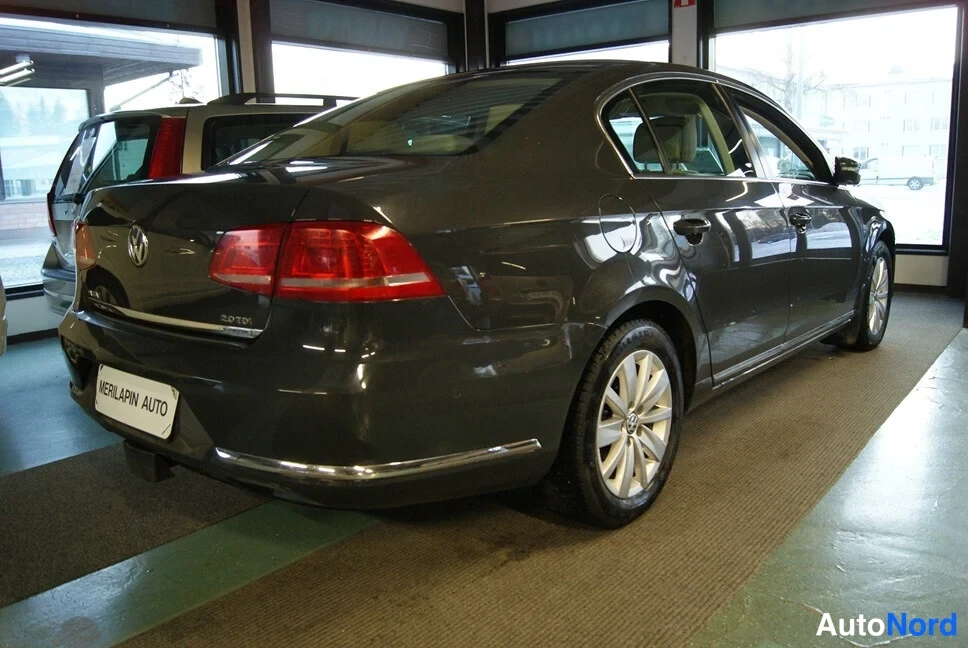 Takaviisto: Tummanharmaan Volkswagen Passat -sedanin takaosa ja vasen kylki näyteikkunan edessä.