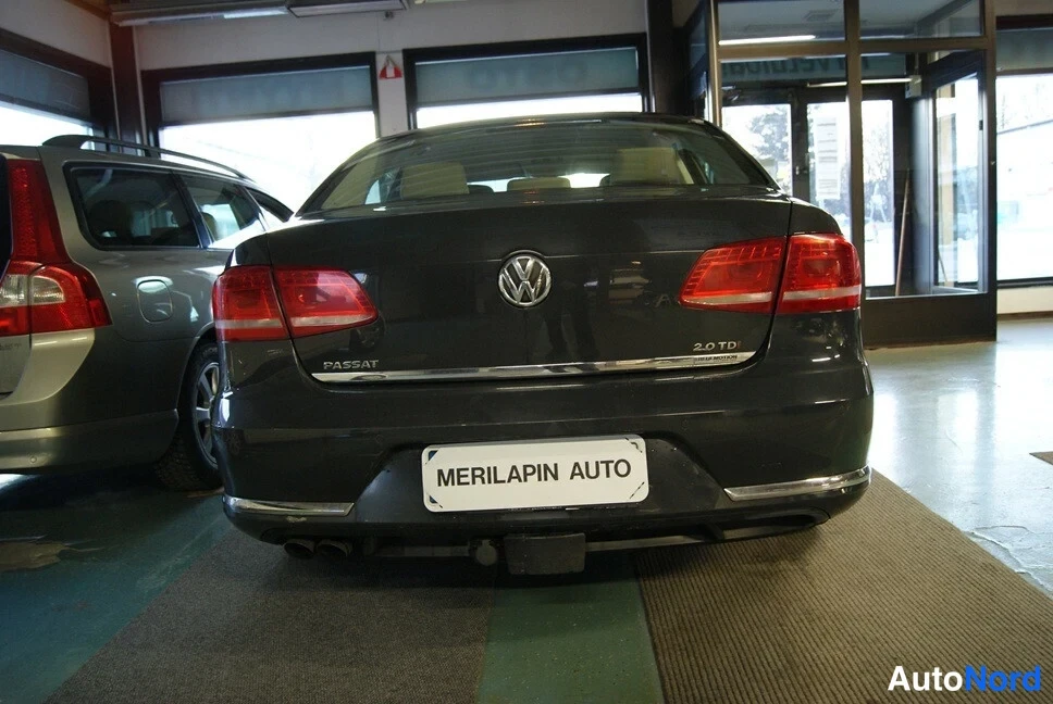 Takaa: Auton takapää, tummanharmaa Volkswagen Passat -sedan, takavalot ja PASSAT-merkintä näkyvissä, perävaunukoukku auki takapuskurissa.