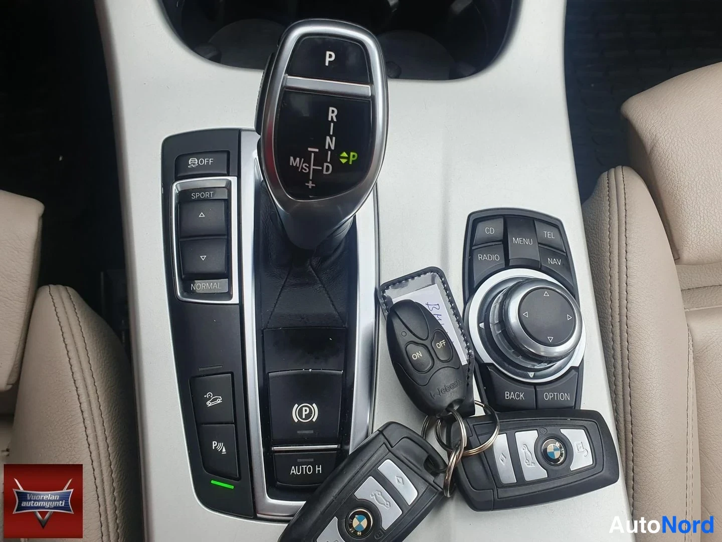 Muu: BMW:n keskikäyttö: automaattivaihteen valitsin, ajotilanappiryhmä, sähköparkkijarru ja iDrive-ohjain; konsolilla kaksi avainlohkoa.