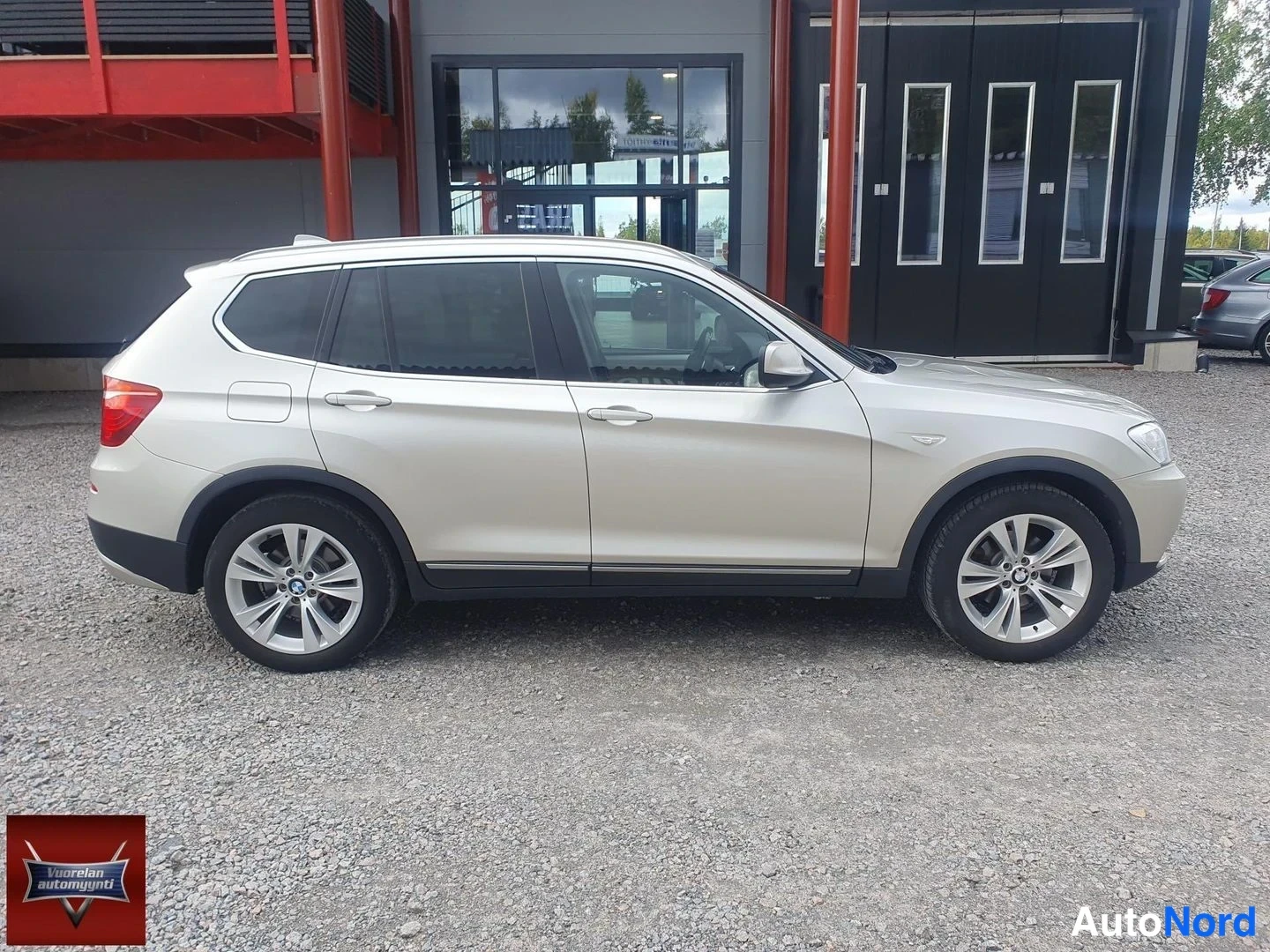Etuviisto, nokka oikealle: Hopeanvärinen BMW X3 -auto kuvattuna sivusuunnassa hieman keulasta; kevytmetallivanteet ja kattokaiteet näkyvät, nokka oikealla ja takaosa vasemmalla.