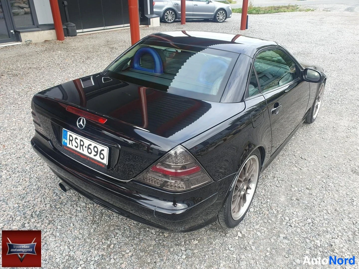 Takaviisto: Musta Mercedes-Benz SLK takaa kolmannesnäkymästä kuvattuna; rekisteritunnus, kiinteä katto ja hopeiset kevytmetallivanteet näkyvät.