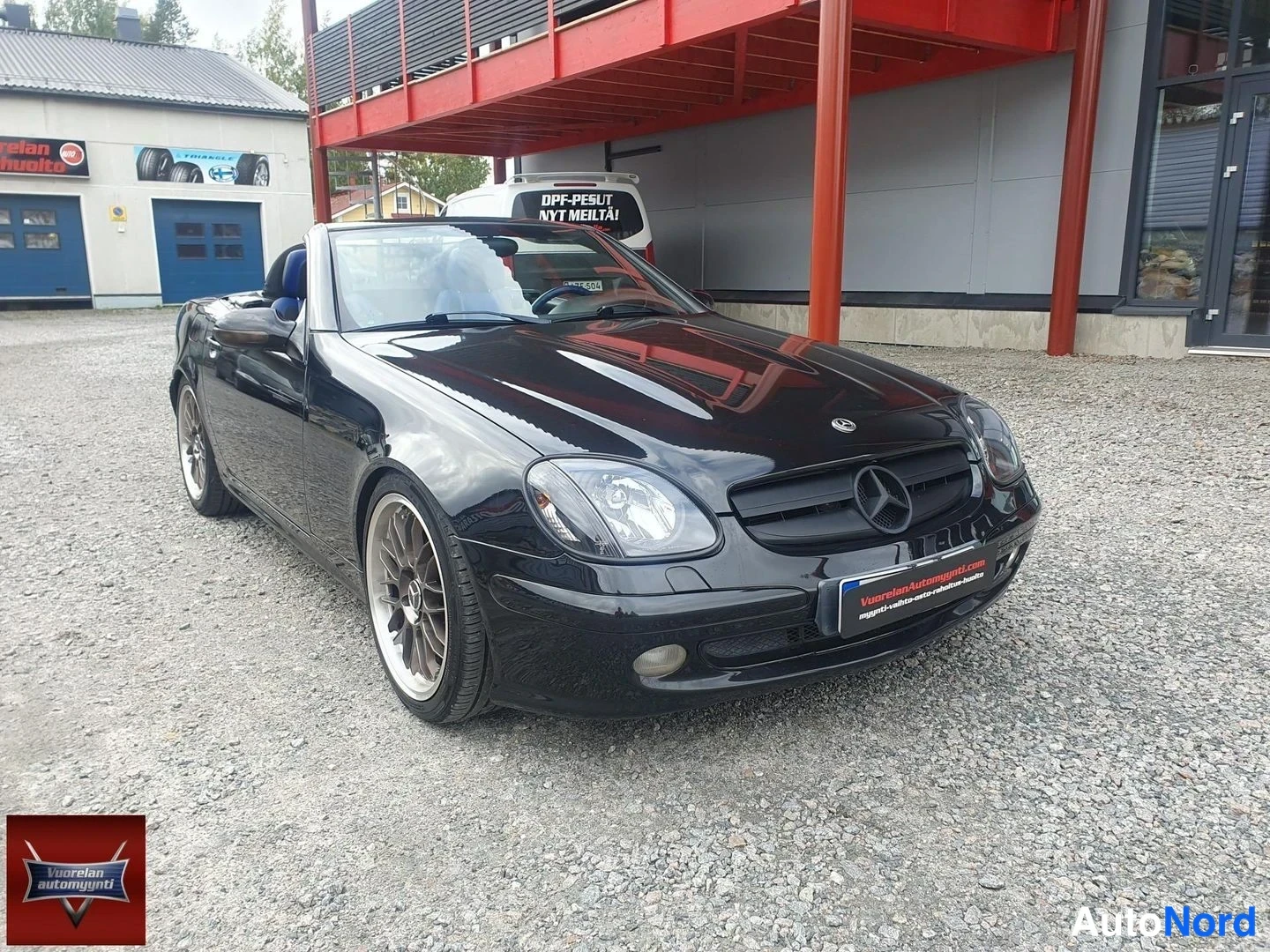 Etuviisto, nokka oikealle: Musta avoauto etuviistosta oikealta: Mercedes-tähti etusäleikössä, ajovalot ja etupuskuri näkyvissä, katto laskettu.