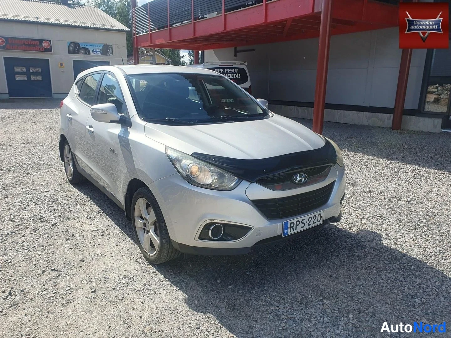 Etuviisto, nokka oikealle: Hopeinen Hyundai ix35 etukulmakuvassa nokka oikealle, rekisterikilpi, konepellissä musta suojaliina.
