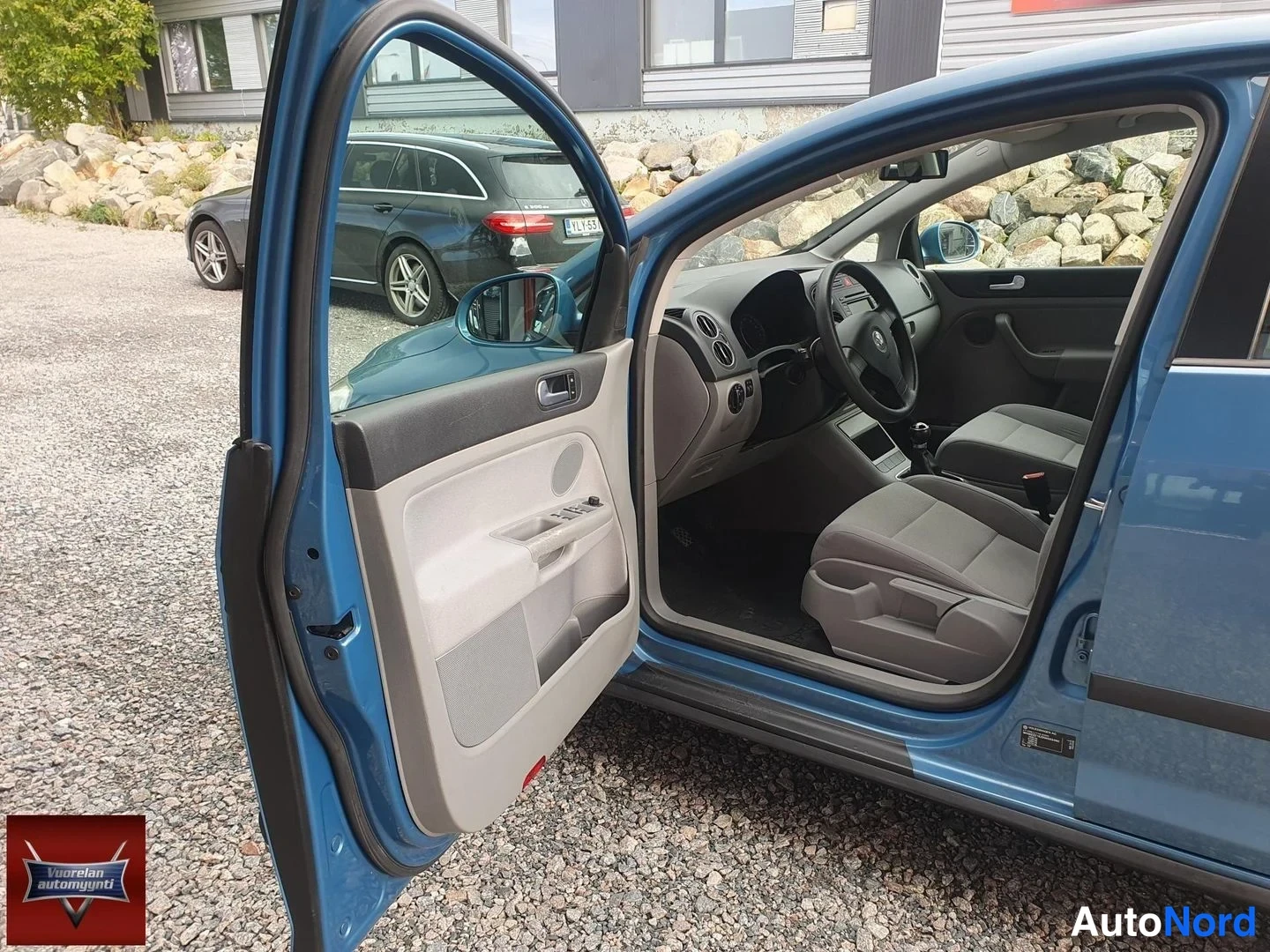 Sivulta: Sinisen Volkswagen Golf Plusin kuljettajan ovi on auki; kuvassa näkyvät ohjaamo, ohjauspyörä, kojelauta ja etuistuimet.