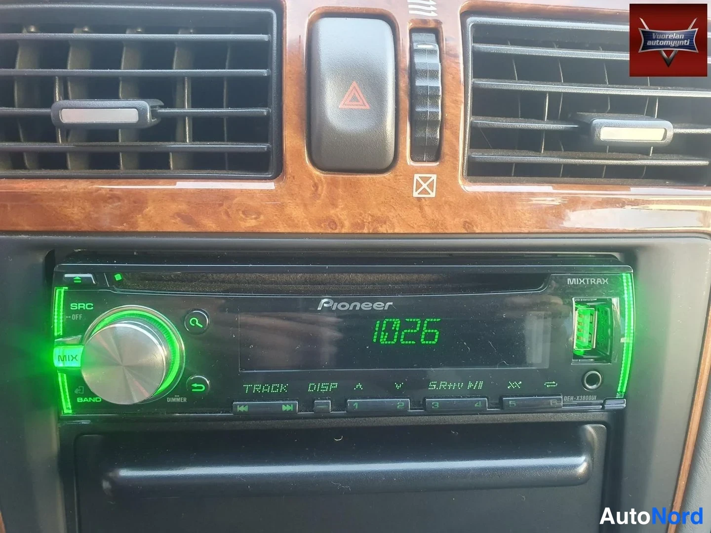 Muu: Ohjaamon keskikäyttöpaneelin sisätilakuva: Pioneer MIXTRAX -autostereo, jonka näytössä lukee 1026 ja jonka painikkeet ja USB-portti on valaistu vihreällä. Stere