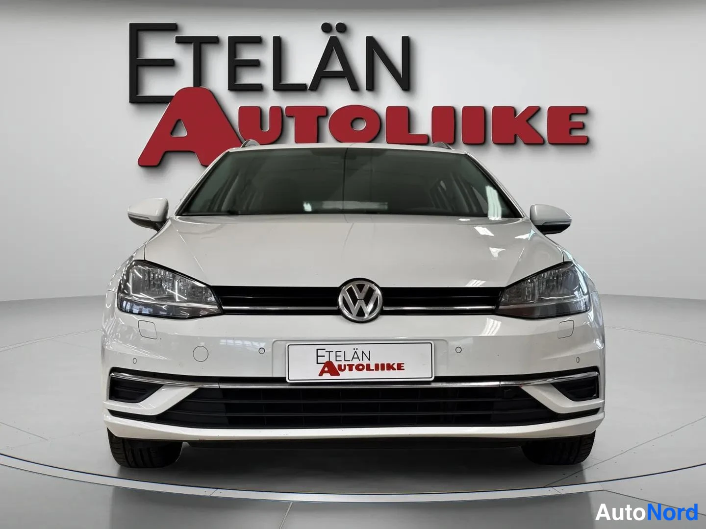 Edestä: Valkoisen farmariauton keula suoraan edestä kuvattuna, VW-merkki ja Etelän Autoliike -kyltti etupuskurissa.