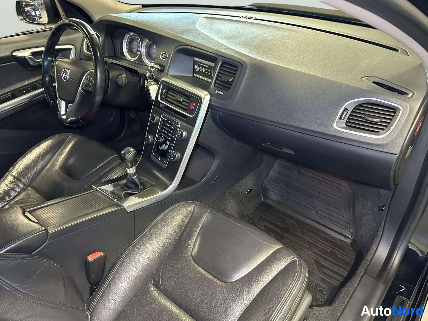 Ohjaamo: Interior cabin view from the passenger side showing dashboard layout, steering wheel and black leather seats.
