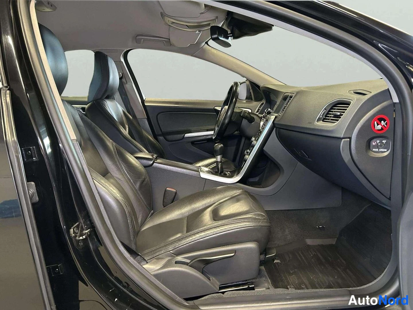 Sivulta: Interior side cabin view through open driver door showing front seat, dashboard, steering wheel and door panel hardware.
