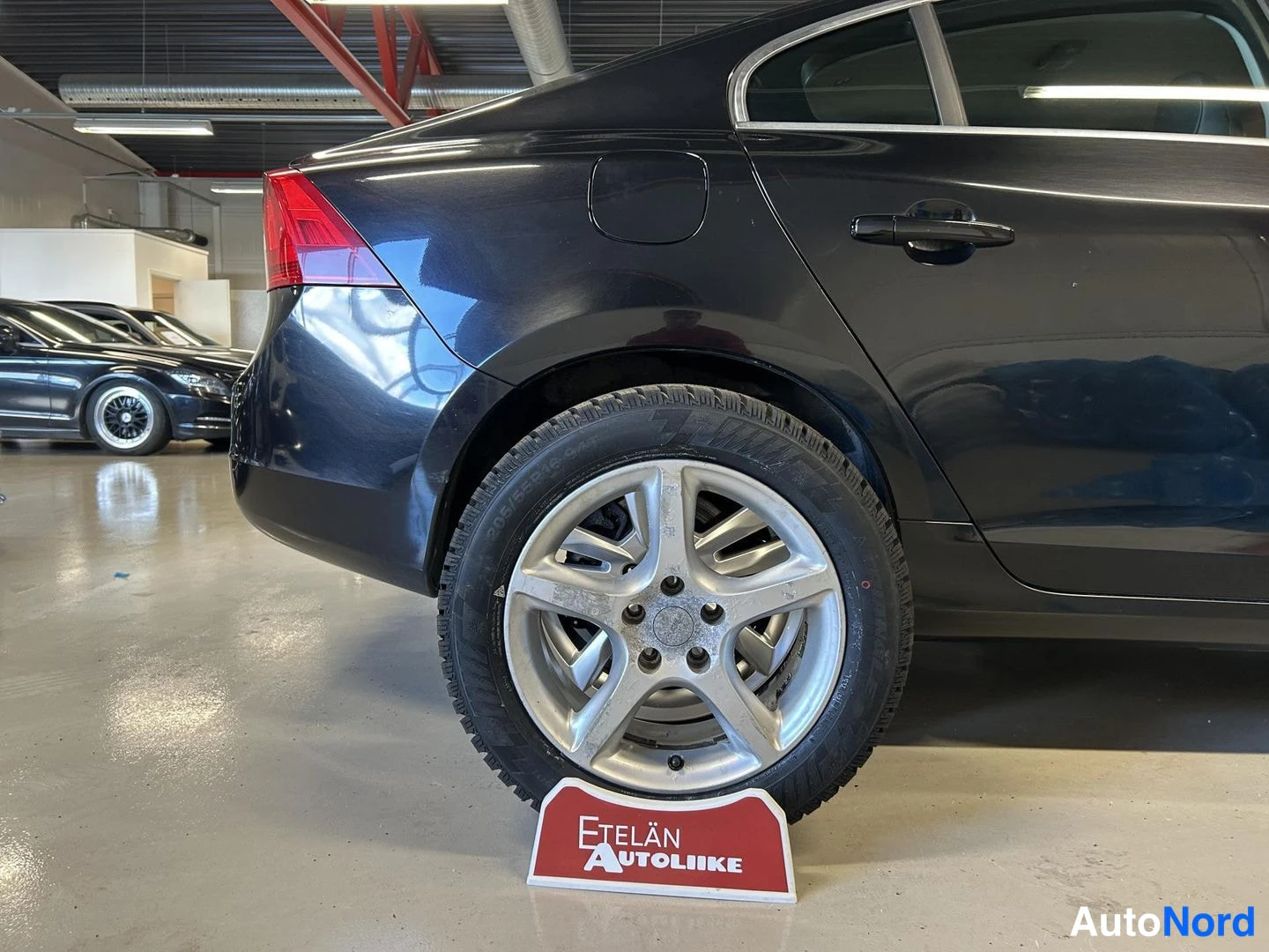 Takaviisto: Auton takaosa ja oikea sivukylki hopeisella viisikaraisella alumiinvanteella, Etelän Autoliike -kyltti renkaan edessä.