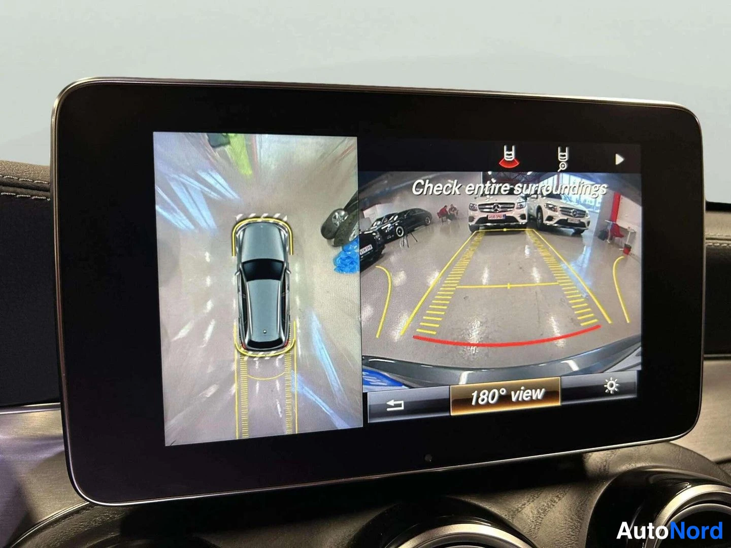 Yksityiskohta: Infotainment-näytön kuva jossa 180 asteen ympäristövalvonta 'Check entire surroundings' ja '180° view' tekstillä.