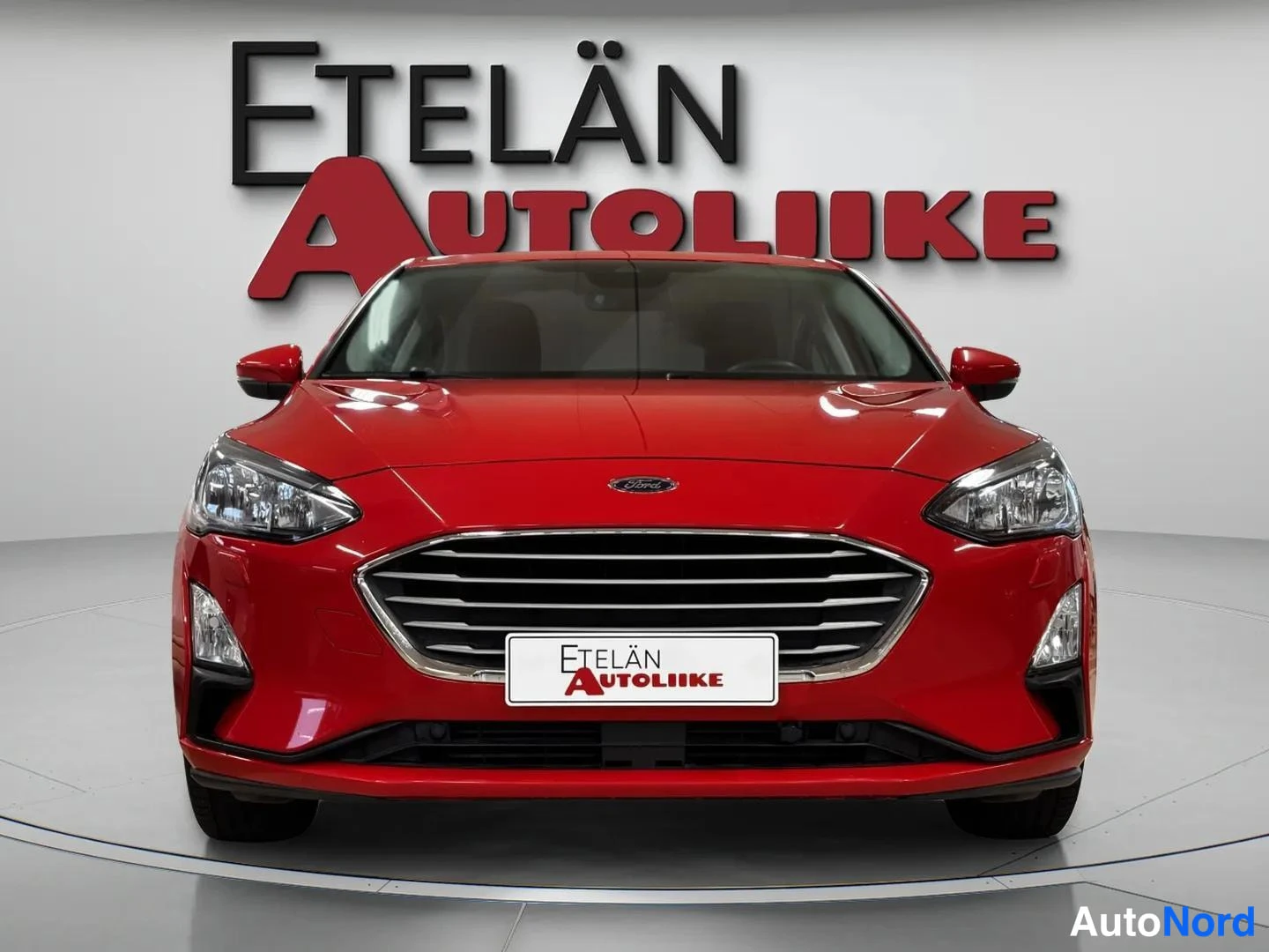 Edestä: Punaisen auton etupää suoraan edestä kuvattuna, Etelän Autoliike -logo taustalla.