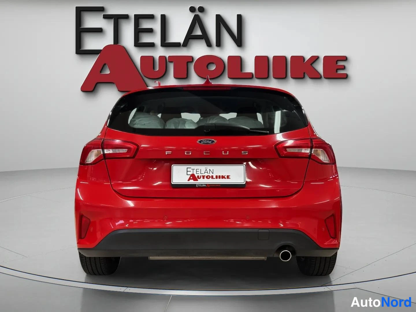 Takaa: Punaisen auton takanäkymä: takavalot, Ford-merkki ja keskellä oleva pakoputki.