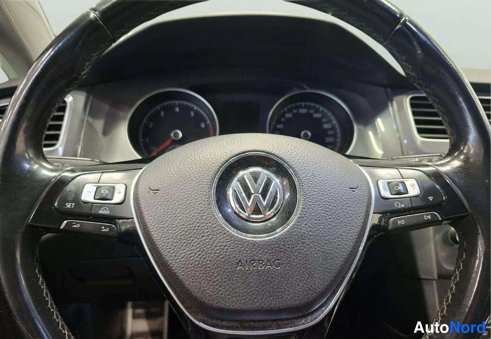 Muu: Ohjauspyörän lähikuva: VW-logon äärellä AIRBAG-teksti, monitoiminapit ja mittariston osa taustalla.
