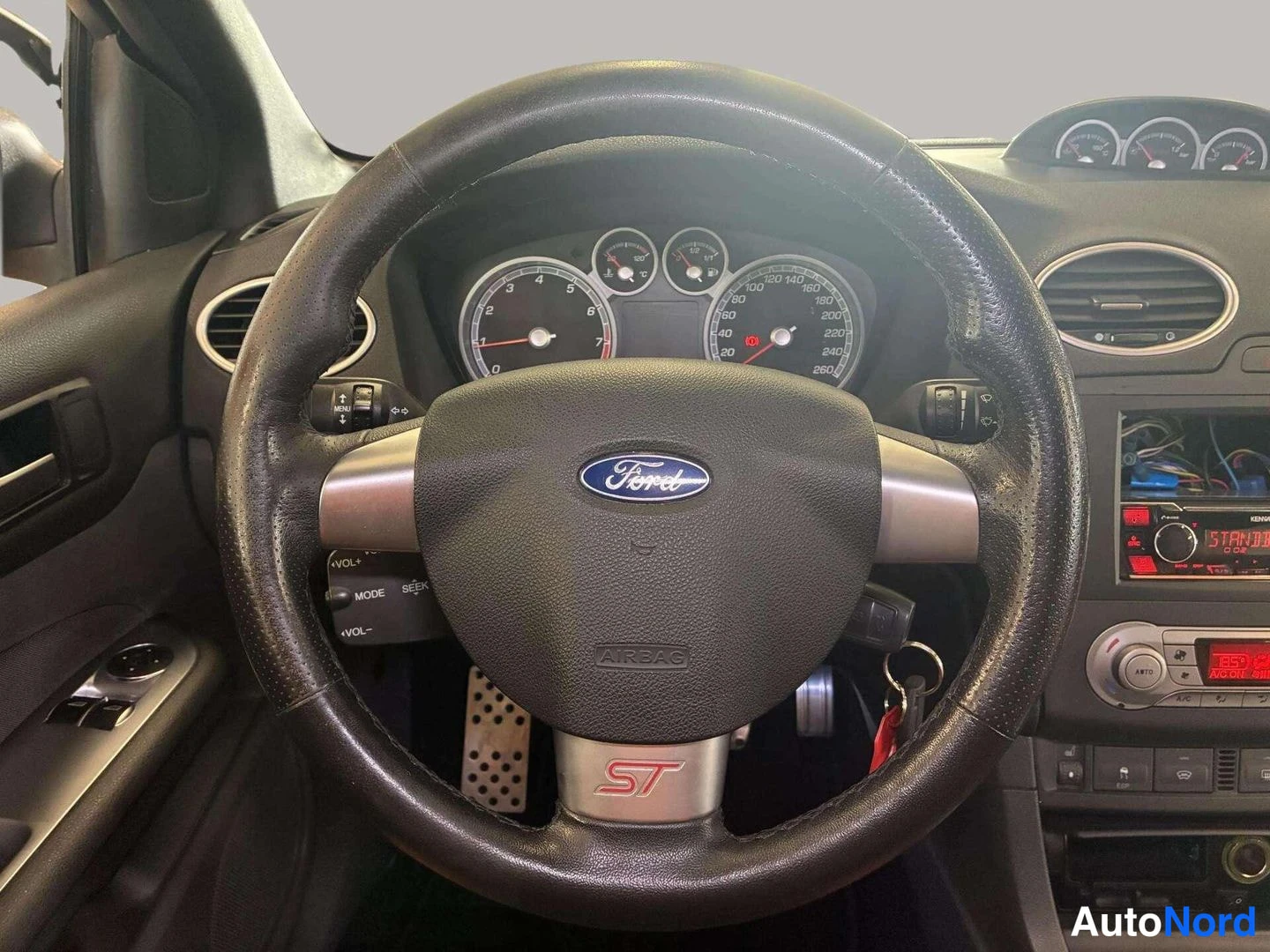 Yksityiskohta: Ford-ohjauspyörä, mittaristo ja radio punaisella näytöllä, avain lukitusrenkaassa.