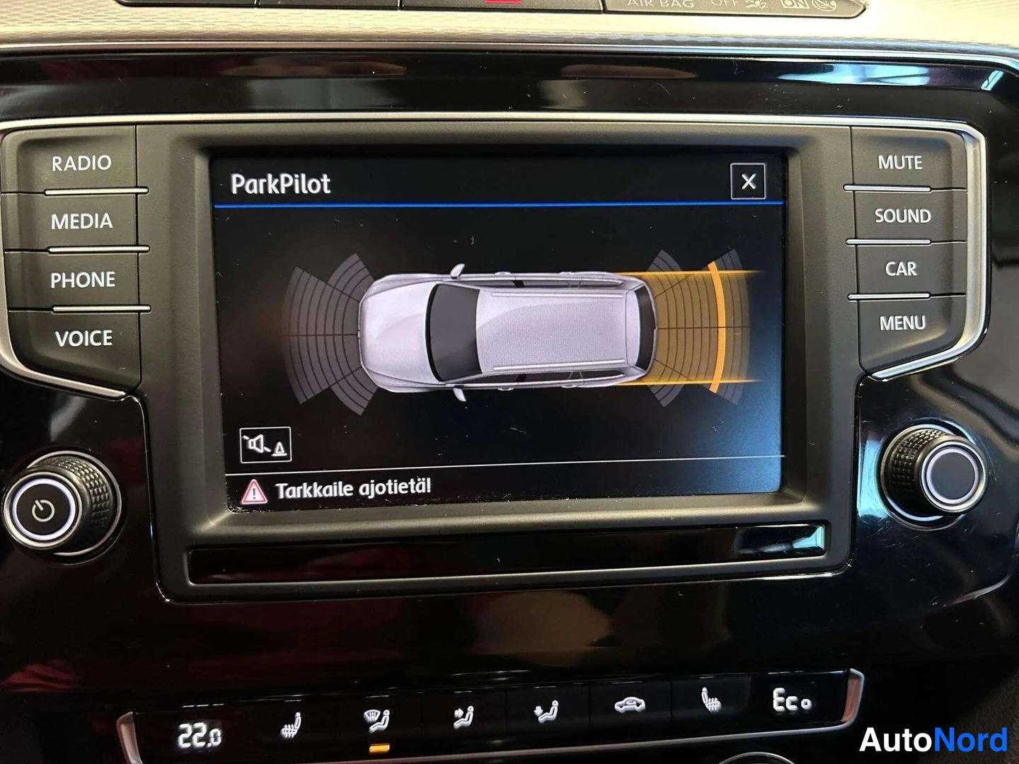 Muu: Volkswagenin kojelaudan näyttö, jossa ParkPilot-tutkakuva ja teksti 'Tarkkaile ajotietäl'.
