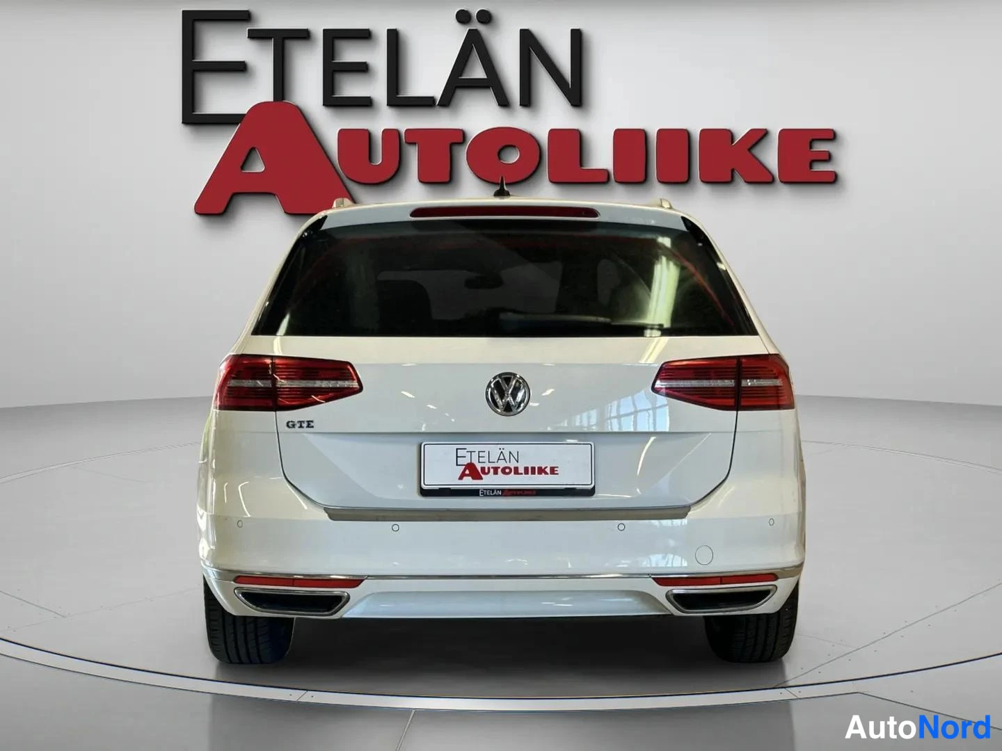 Takaa: Valkoisen farmariauton takanäkymä, punaiset takavaloja ja Volkswagen-merkki peräluukussa studioympäristössä.