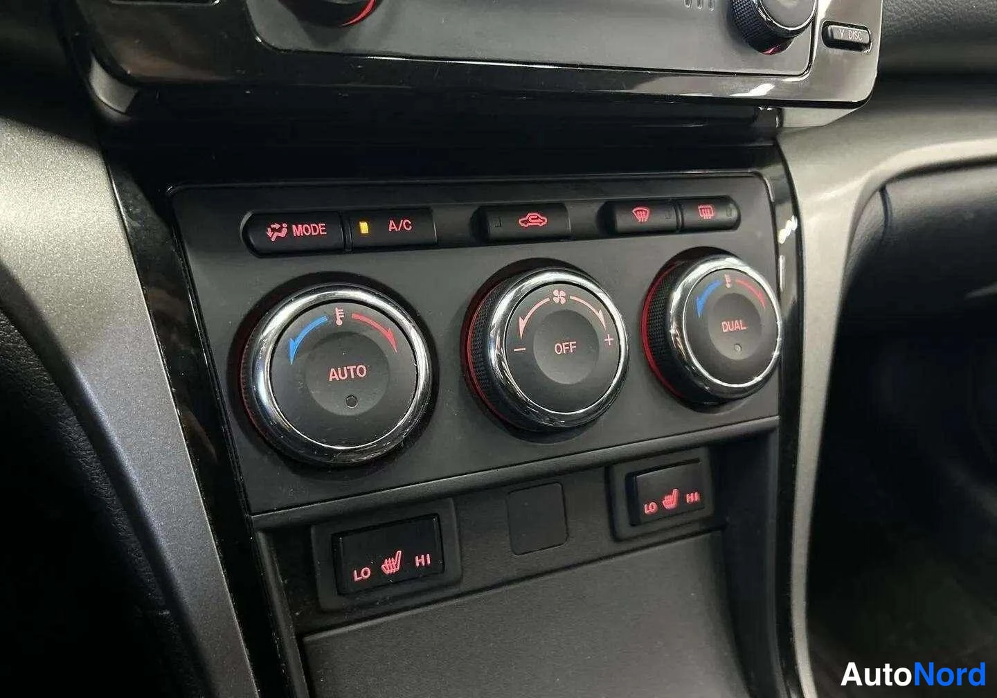 Etuviisto, nokka oikealle: Hallintapaneelin nappien: MODE, A/C ja AUTO-merkinnät; vetokoukku-ikkunan suljin saa nineet OFF ja QUA.