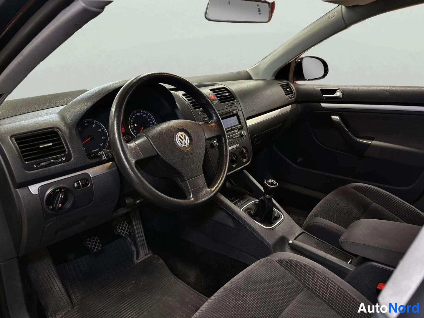 Muu: Ohjaamo vasemmalta: Volkswagen-ohjauspyörä, analogiset mittarit, manuaalivaihteiston vaihdekeppi ja tummat kankiistuimet.