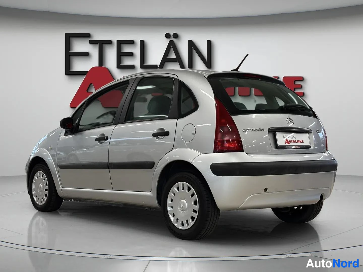 Takaviisto: Hopeanvärinen Citroen C3 -henkilöauto kuvattu takaosasta ja vasemmalta sivulta autonäyttelytilassa.