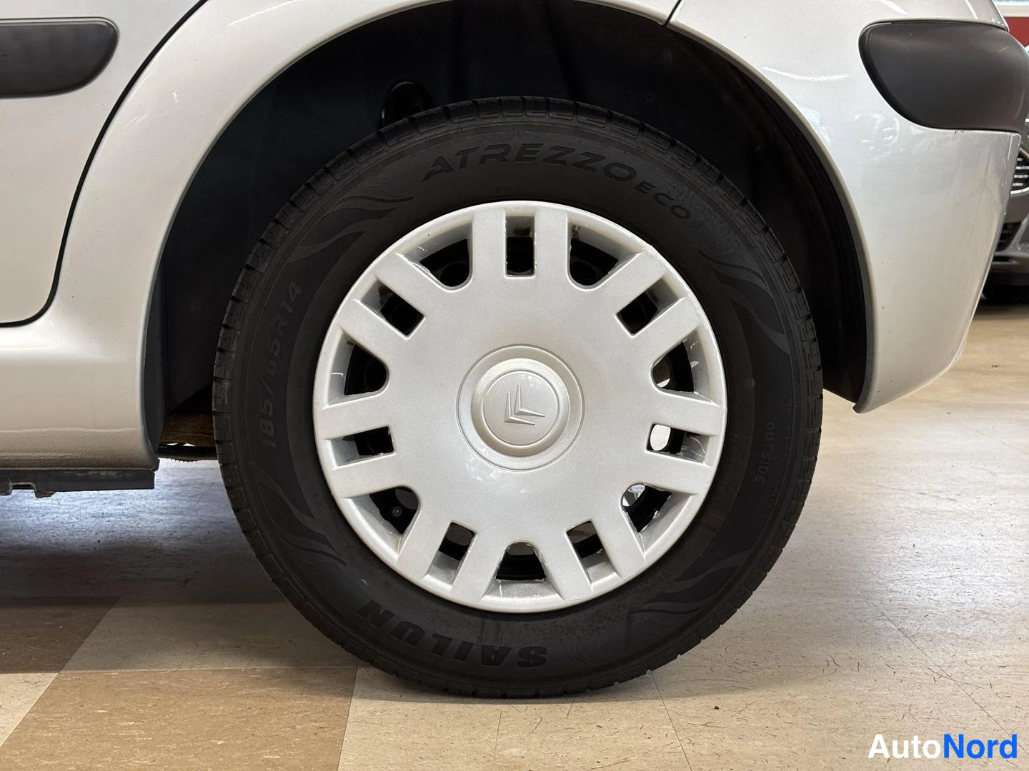 Sivulta: Sivun pyörän lähikuva: hopeinen peltivanne Citroenin embleemillä ja renkuksessa teksti ATREZZO ECO.