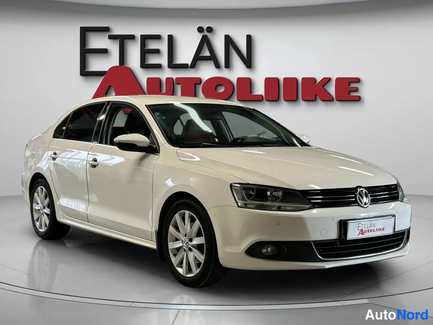 Etuviisto, nokka oikealle: Valkoinen Volkswagen Jetta -sedan etuviistokuva oikealta, etusäleikkö ja ajovalot näkyvät.
