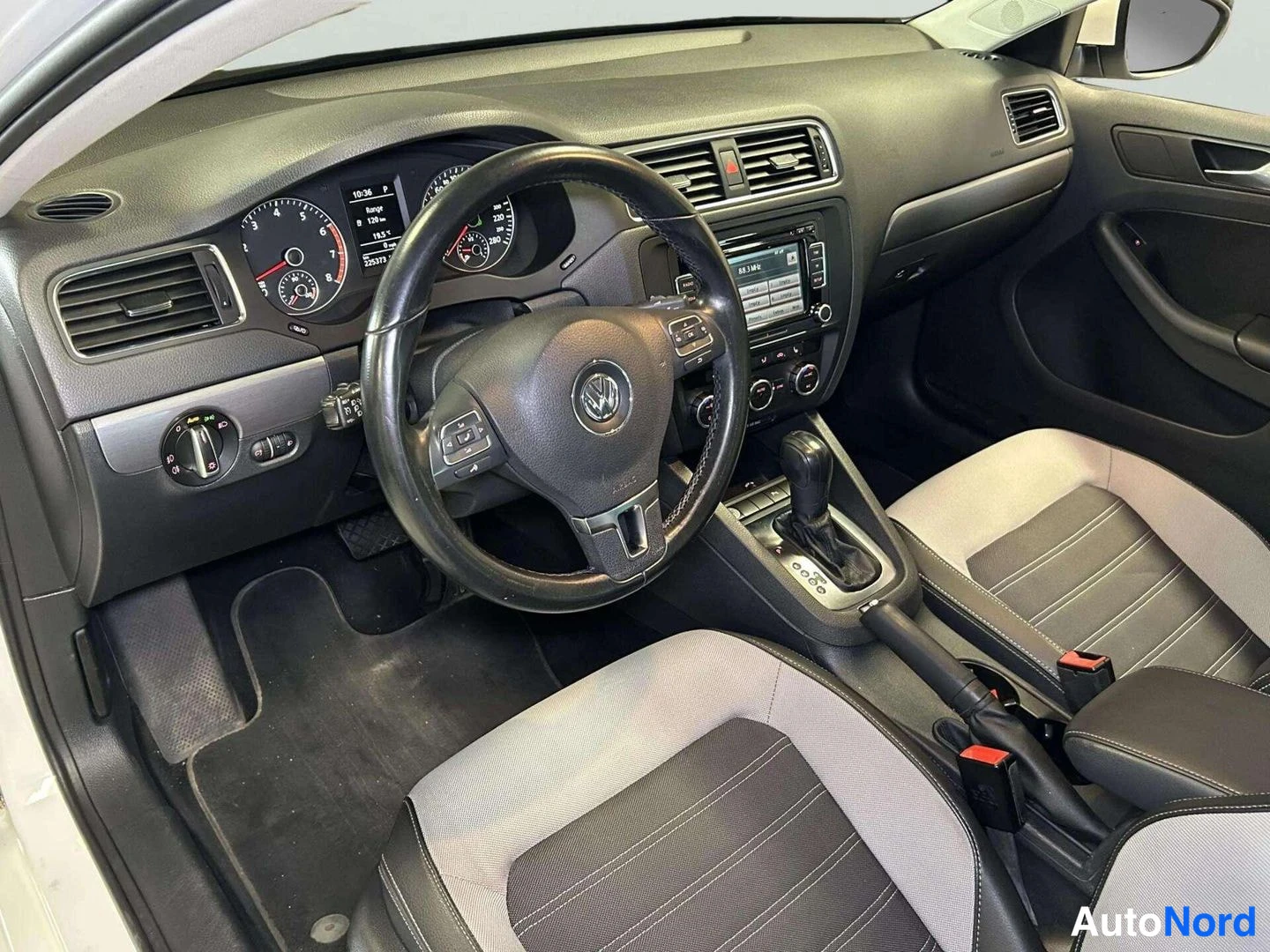 Edestä: Volkswagenin kuljettajan puolen etuistuin ja kojelauta: mittaristo, monitoimiratti, kosketusnäytön radio, automaattivaihteiston valitsin ja kaksivärinen etuistu