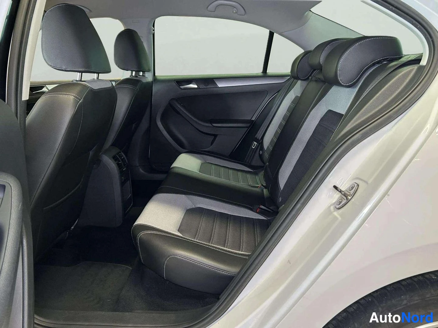 Takaistuimet: Back seats from the left rear door. The seatbacks and headrests are upholstered in black leather with light grey fabric inserts on the seat centre and back. Whi