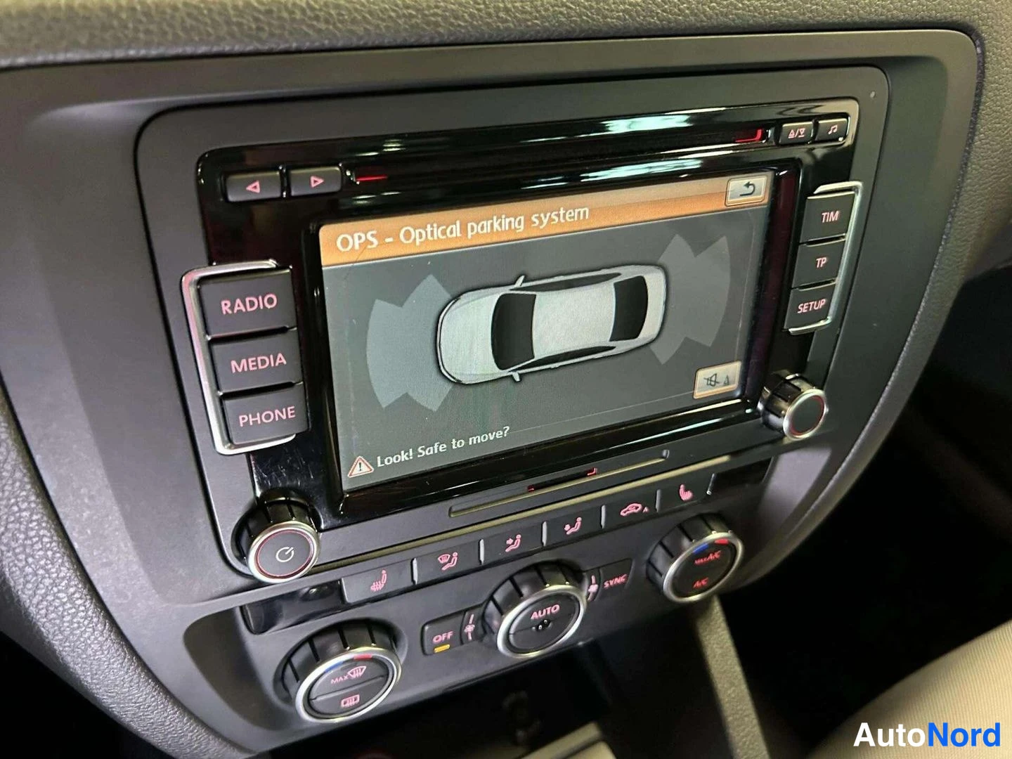Edestä: Radiopaneelin lähikuva, näytöllä teksti 'OPS – Optical parking system' ja auton ympärysmitan grafiikka.