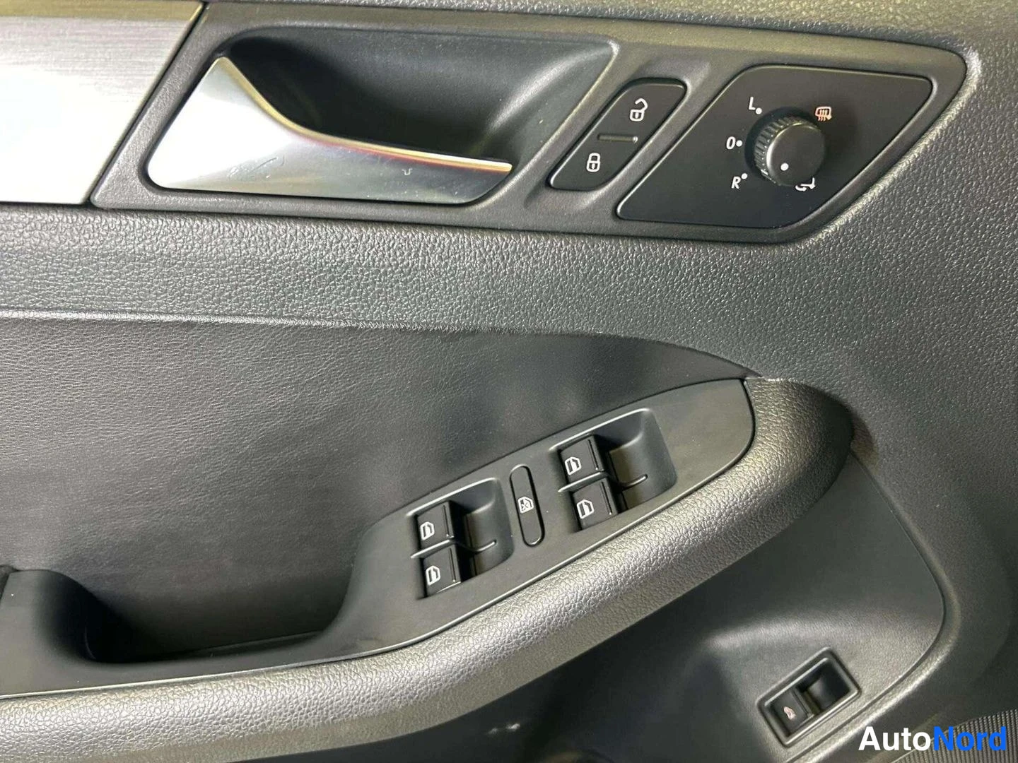 Yksityiskohta: Driver side door panel control cluster with window switches and mirror adjustment.