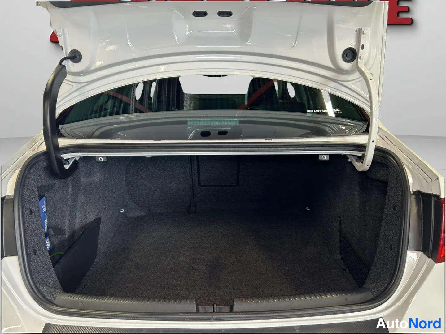 Tavaratila: White vehicle trunk interior with rear hatch open showing carpeted cargo area.