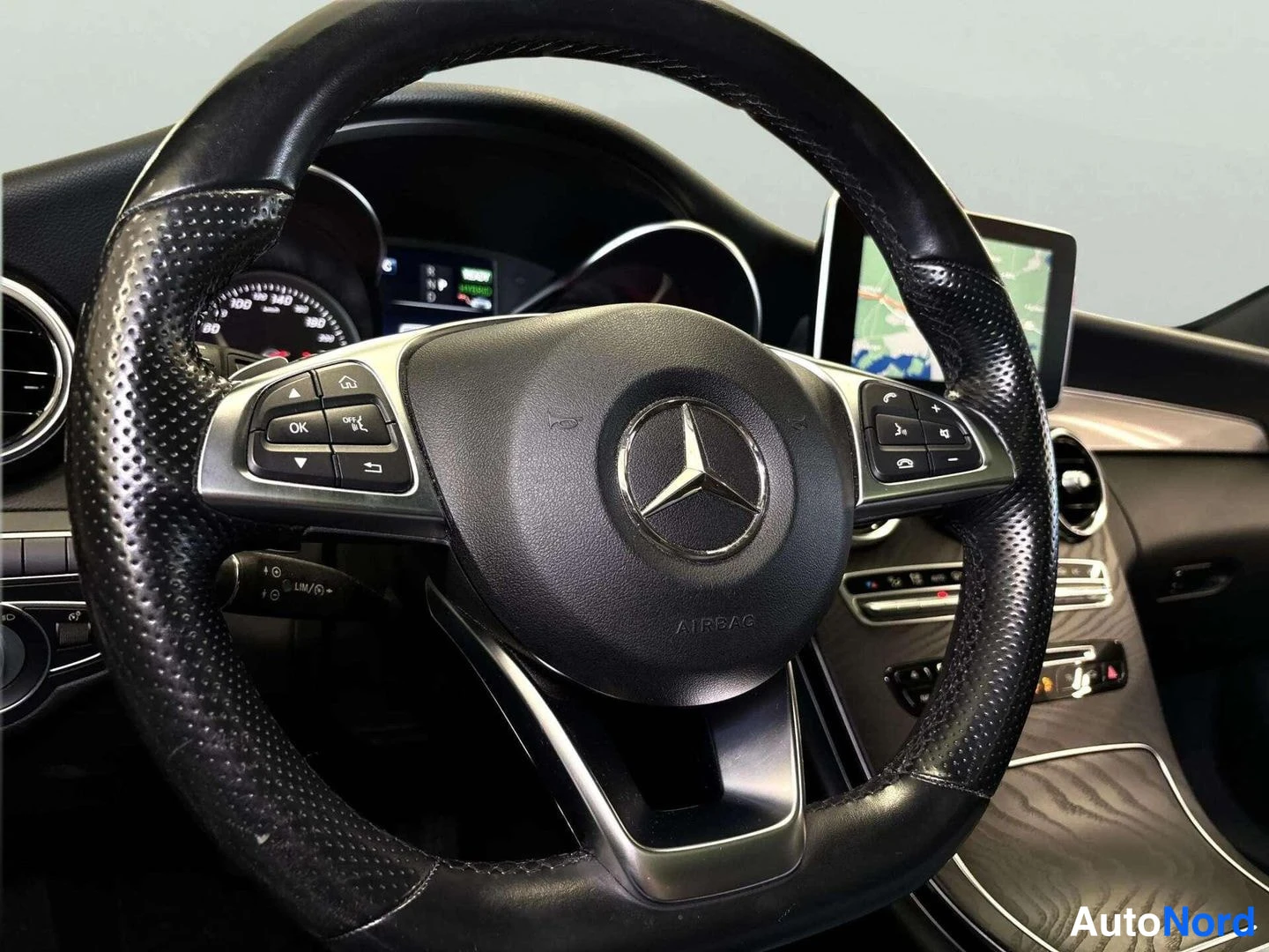 Muu: Mercedes-Benz-ohjauspyörä AIRBAG-tekstillä ja monitoimipainikkeet, kojelauta ja karttanäyttö taustalla.