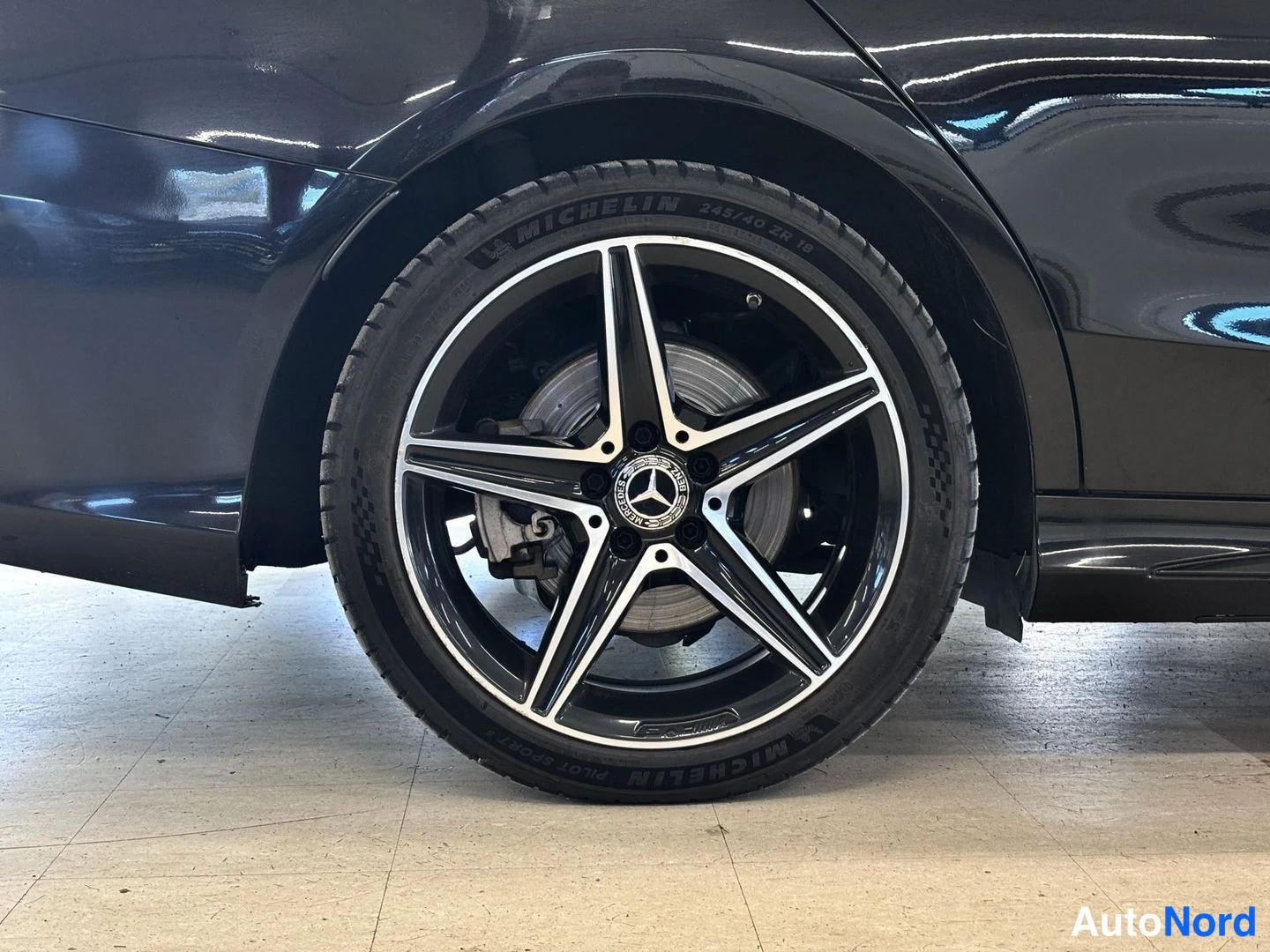Yksityiskohta: Mustan auton takapyörä ja viisisakarainen Mercedes-kevytmetallivanne, Michelin-renkuissa teksti 245/40 ZR 18.
