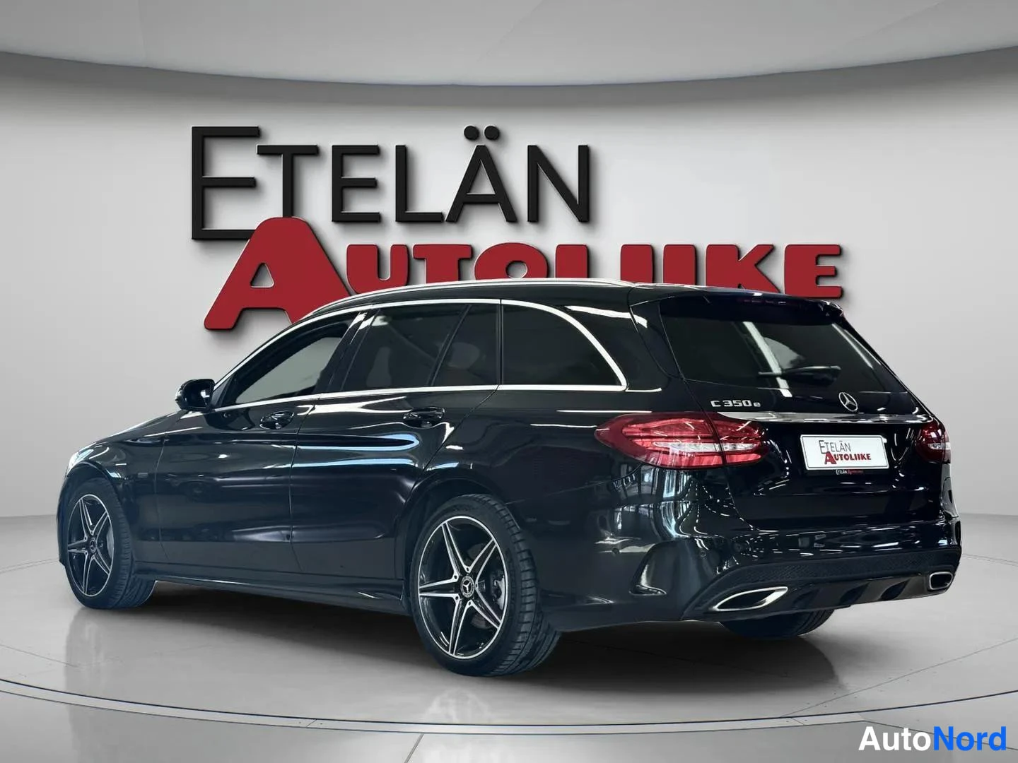 Takaviisto: Auton takaosa ja vasen sivu kolmasosakulmassa; musta Mercedes-Benz C 350 e -farmari studiovaloissa.