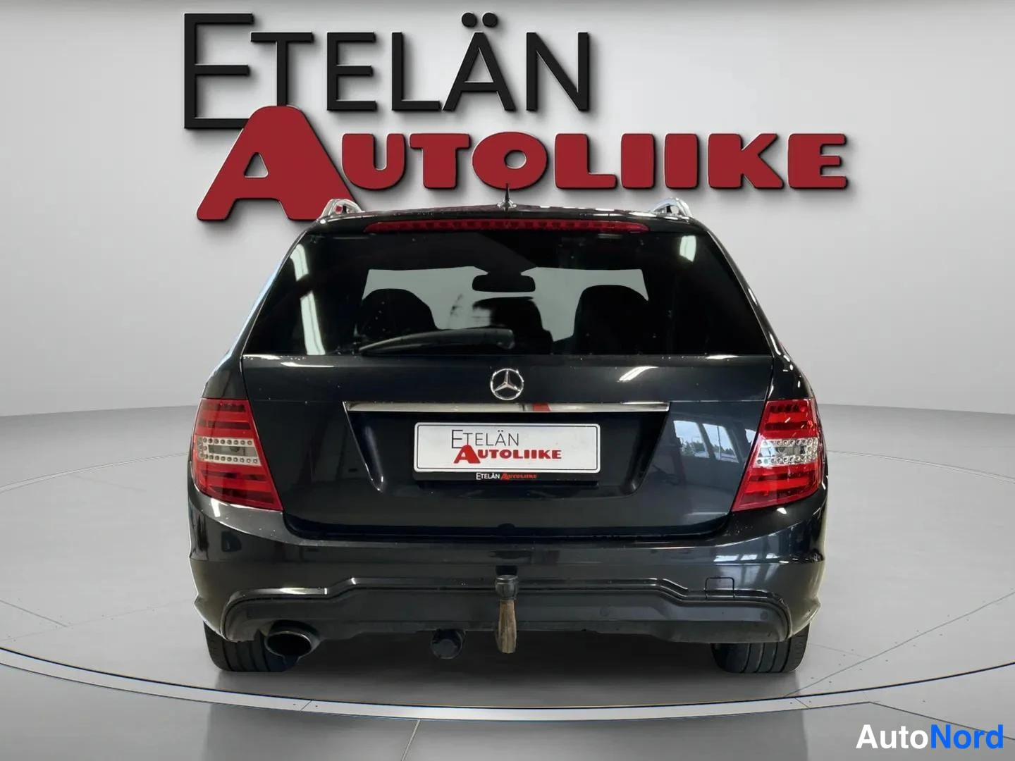 Takaa: Mustan farmaritakin olevan Mercedes-Benzin takaosan suora taka näkymä, jossa näkyvät takavalot, peili, tavaratilan luukun kansi ja Mercedes-tähti.