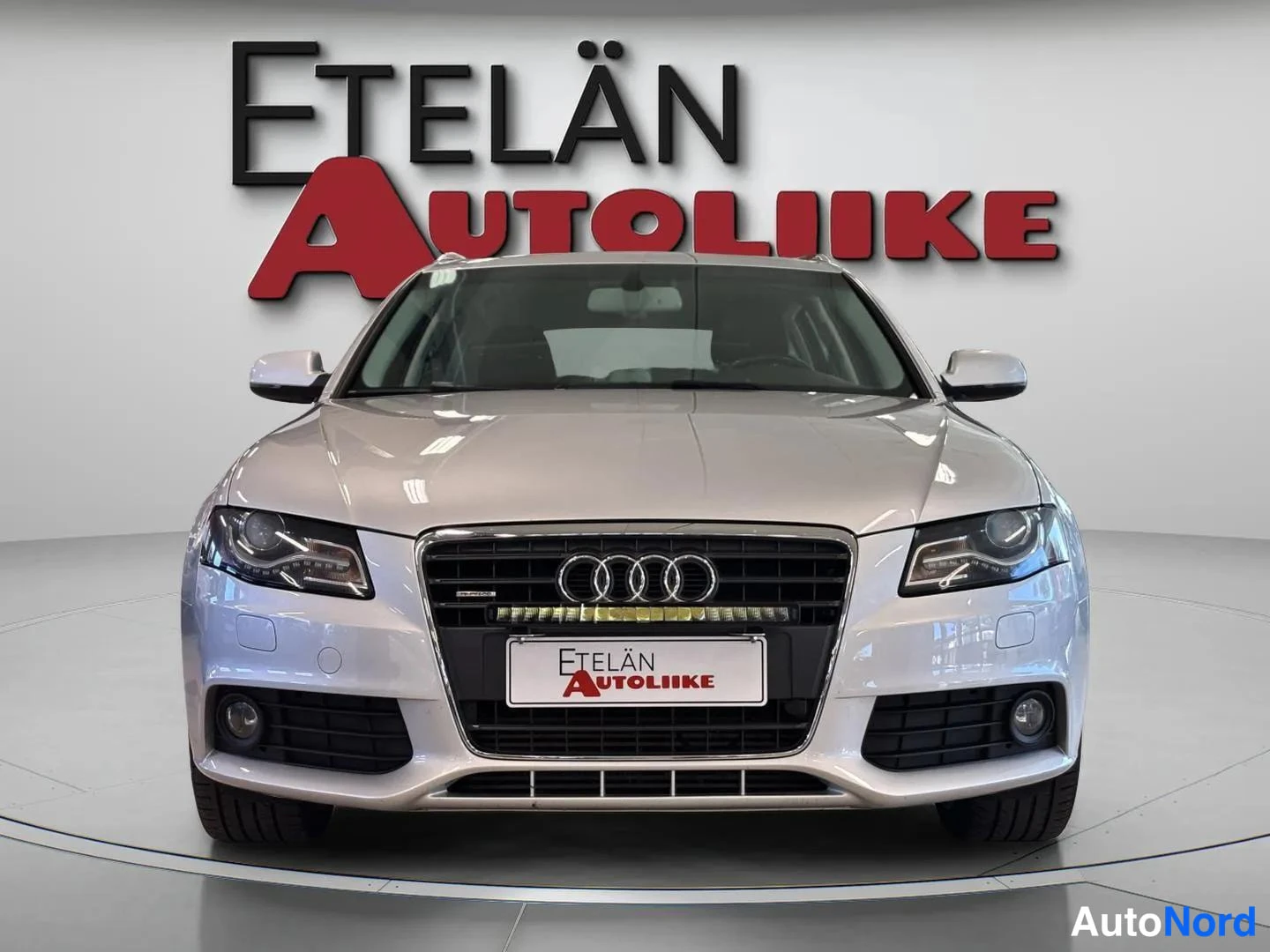 Edestä: Frontal shot of an Audi A4 Avant with grille and headlights against a white wall with 'ETELÄN AUTOLIIKE' text