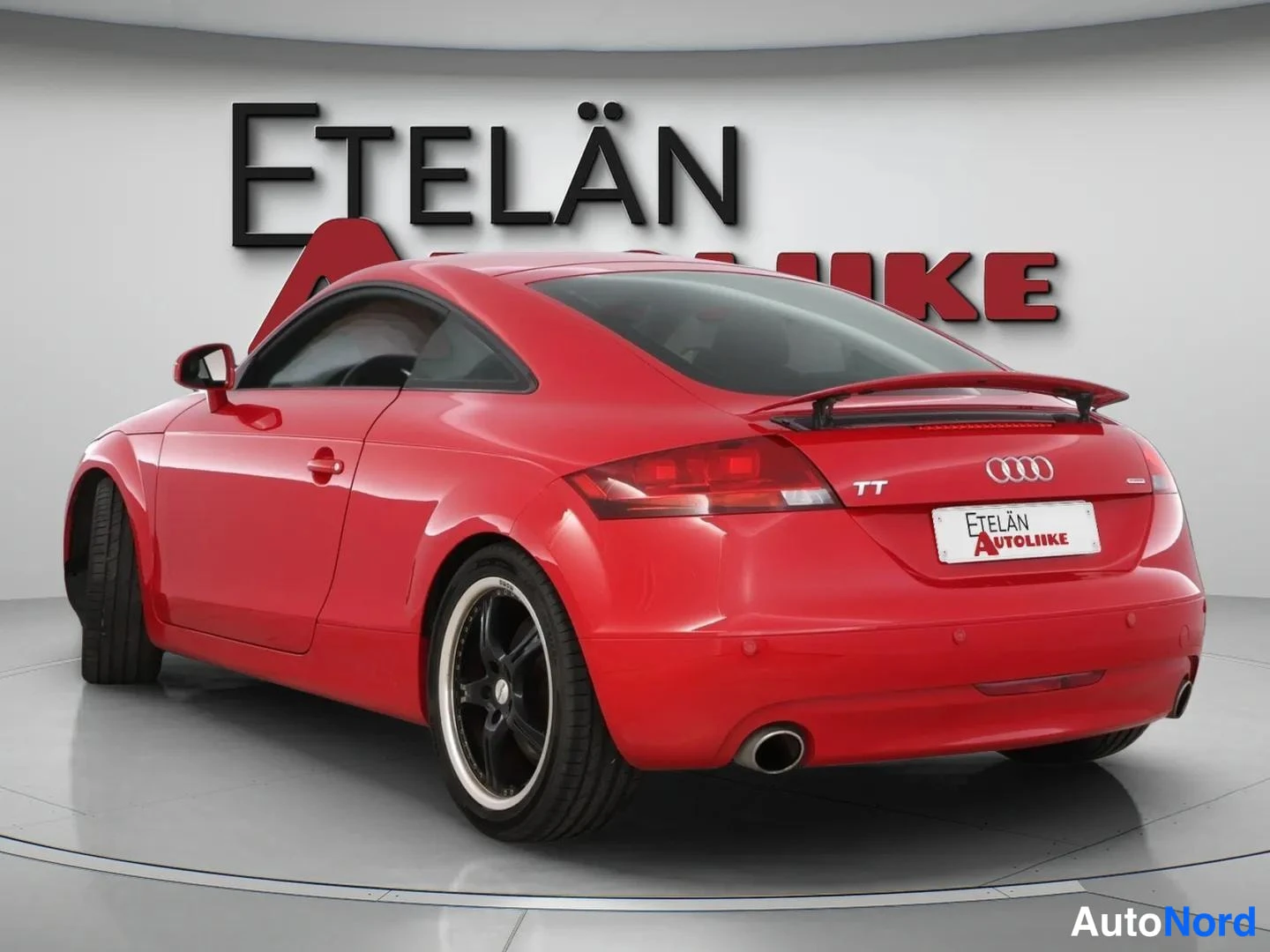 Takaviisto: Punainen Audi TT Coupé takaviistosta, bootlid-spoileri nostettuna ja TT-merkki, Etelän Autoliike -rekisterikilpi.