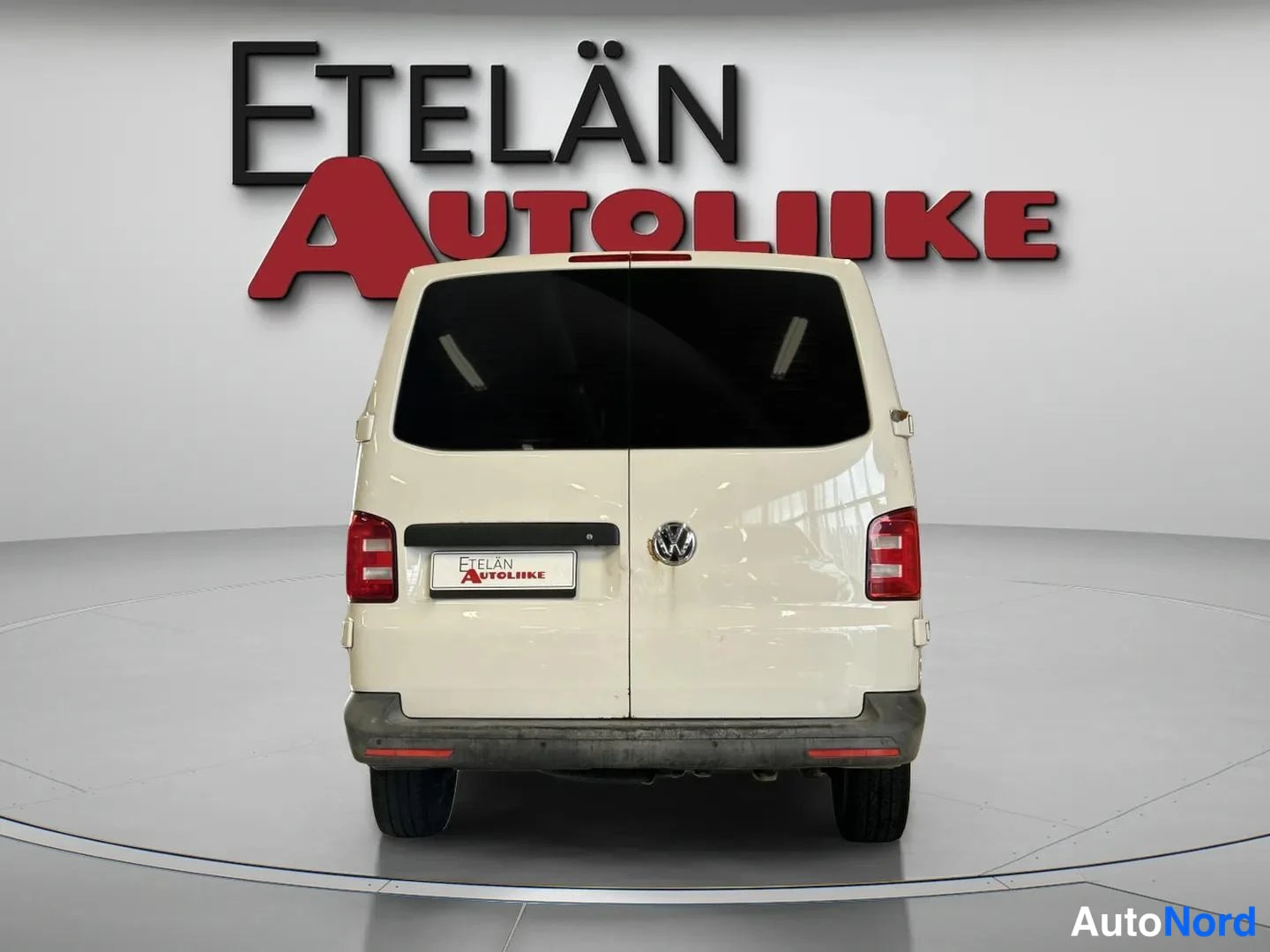 Takaa: Valkoinen pakettiauto suoraan takaa kuvattuna, tummat takamarketit, korinpohjan kulumat näkyvät palkilla